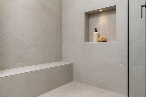 Custom shower niche and bench installation in Calgary with large-format wall tile, precise grout lines, and premium finished tile detail